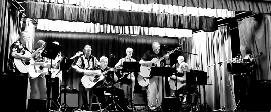 Guitars + members performing on stage.