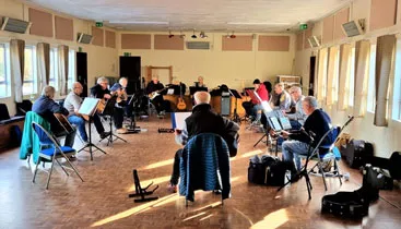 Guitar + group practicing at Woodlands Village Hall showing members playing guitars in a circle